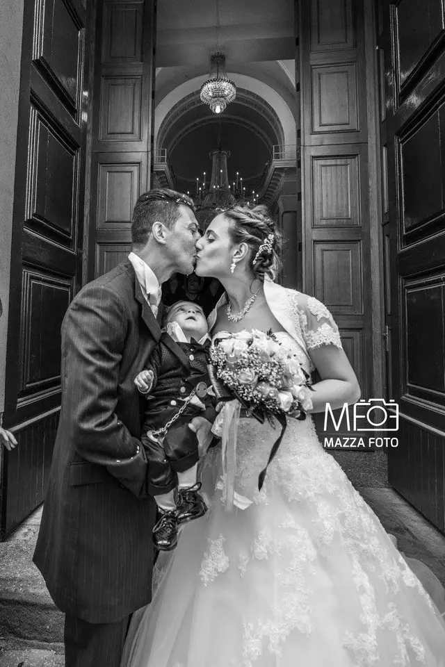 Bacio degli sposi sulla porta della chiesa con il loro bambino