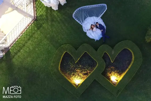 Vista dal drone: gli sposi sul prato tra due aiuole a forma di cuore